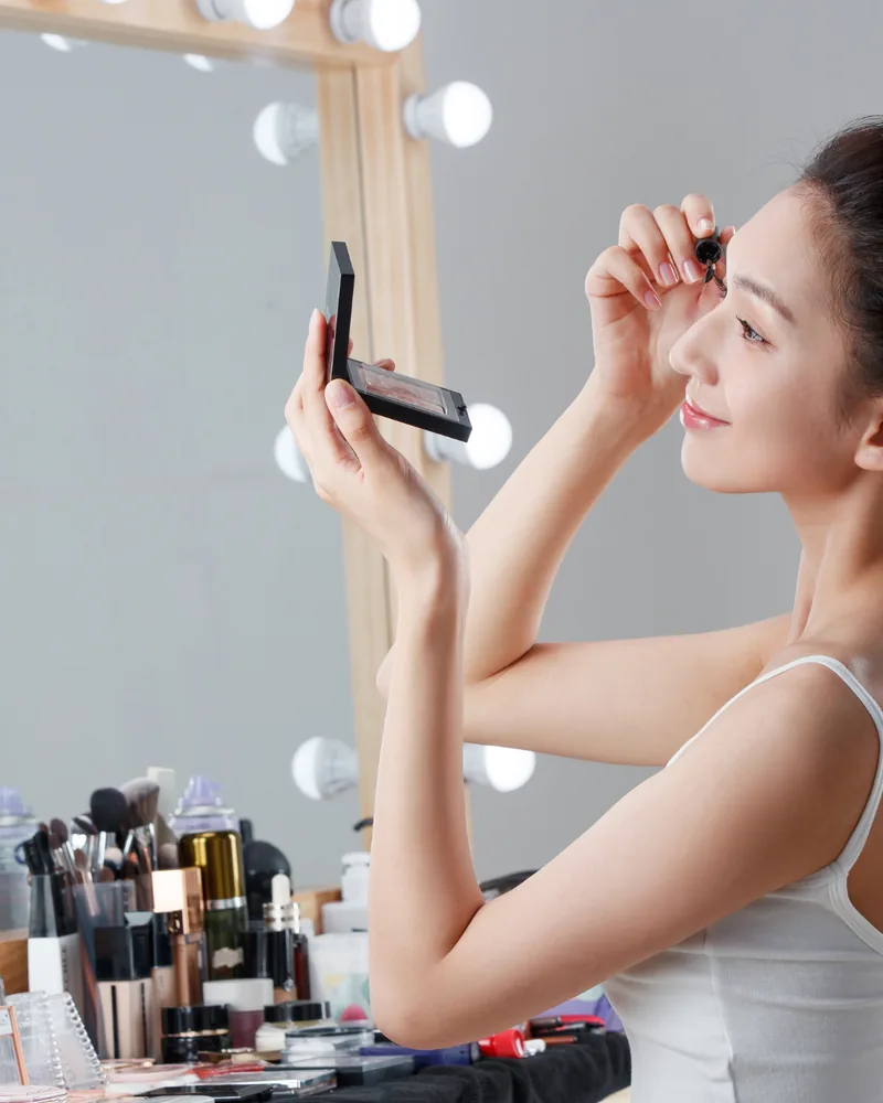 Teilnehmerin schminkt sich im Make up Workshop vor dem Spiegel